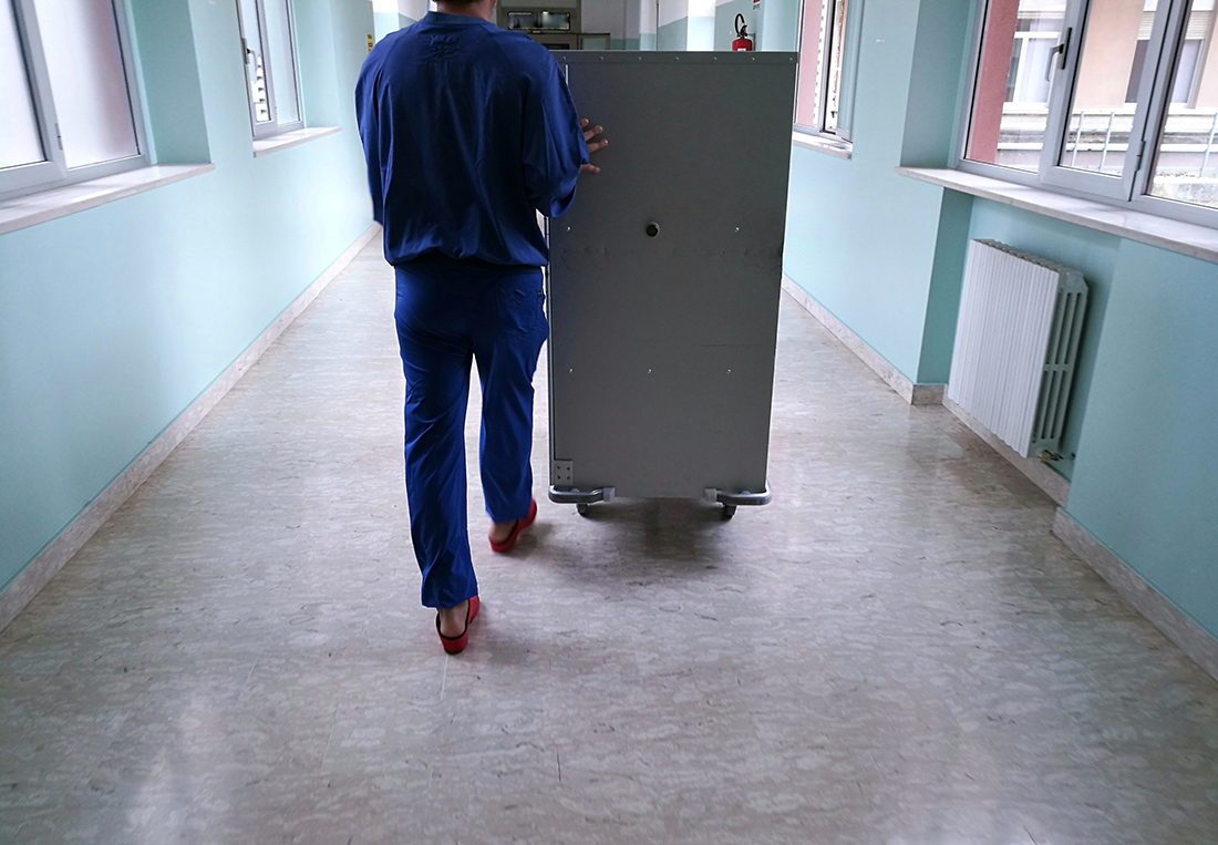 Hospital employee pushes a large food delivery container with one hand