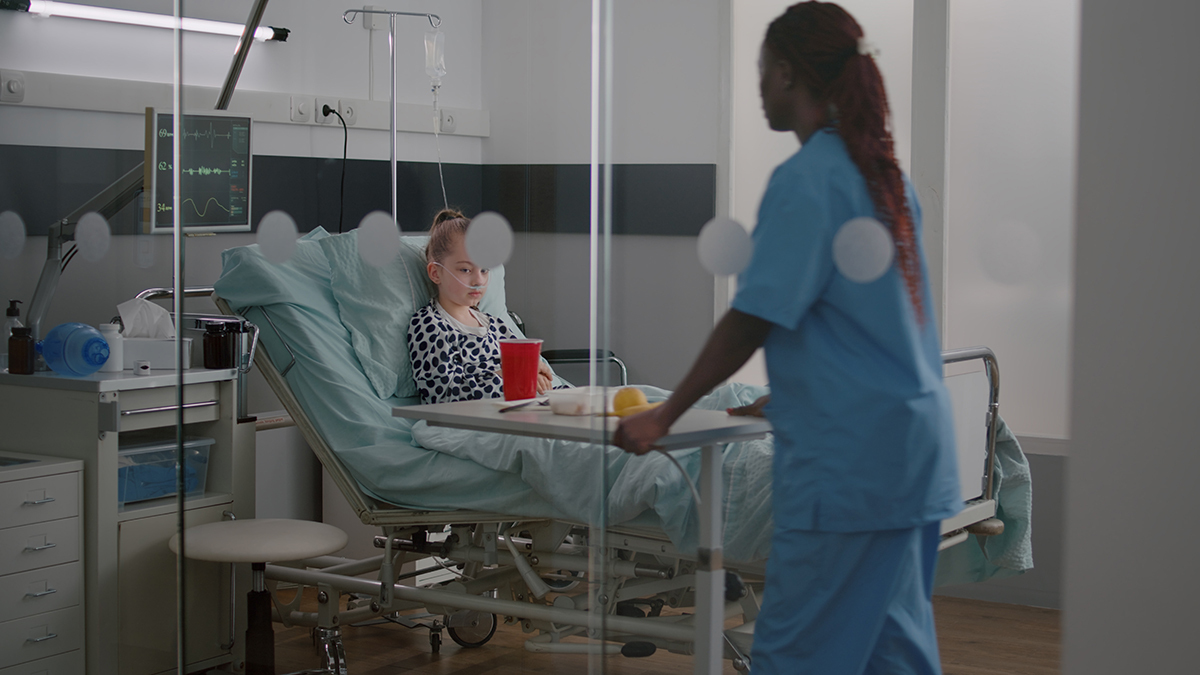Nurse wheels a patient's meal cart into a hospital room.