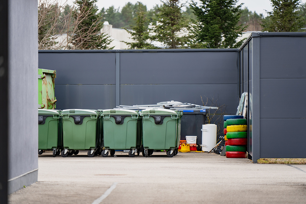 Row of mobile waste bins in an outdoor service area.